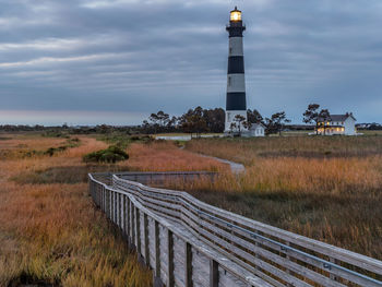 Lighthouse on field against sky