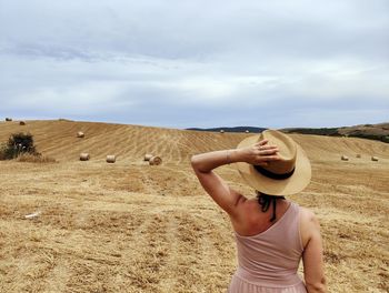 Rear view of woman standing on field against sky