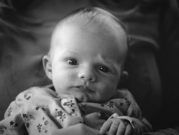 Portrait of cute baby girl lying on bed at home