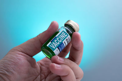 Midsection of person holding bottle against blue background