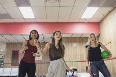 A young woman bowling with friends.