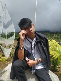 Young man using mobile phone while sitting outdoors