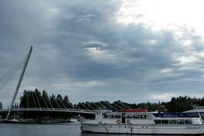 Boats in river against cloudy sky