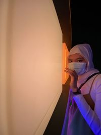 Portrait of woman standing against wall