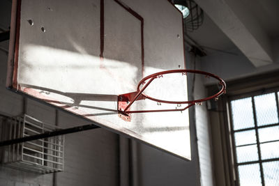 Low angle view of indoor basketball hoop missing a net in a middle school gym 