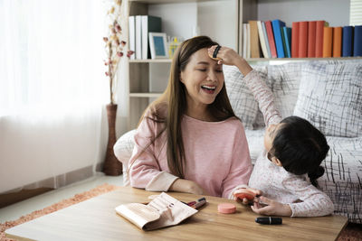 Happy mother and daughter sitting at home