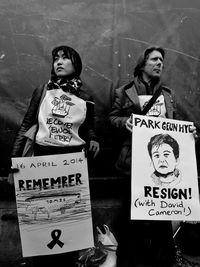 Woman holding poster while standing against wall