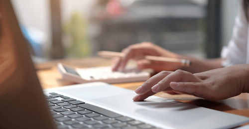 Close-up of woman using laptop on table