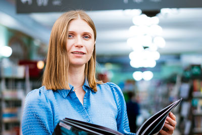 Cute view of woman holding an open paper book, reading bestseller from