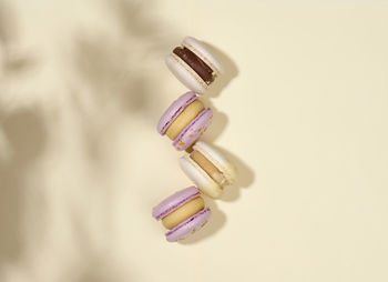 Baked macarons with different flavors on a beige background, top view