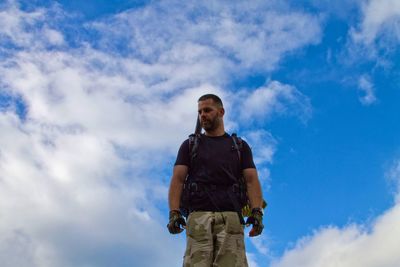 Low angle view of man standing against cloudy sky