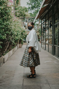 Rear view of woman walking on footpath in city