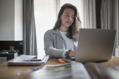 Portrait of young woman using phone while sitting on table