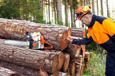 Professional lumberjack with protective workwear and chainsaw working in a forest