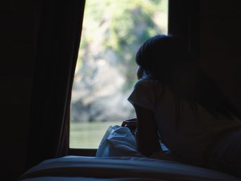 Woman looking through window at home