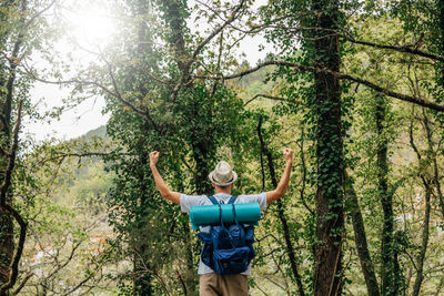 Man with backpack in nature with arms raised