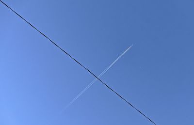 Low angle view of power lines against clear blue sky