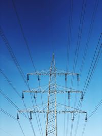 Low angle view of electricity pylon against blue sky