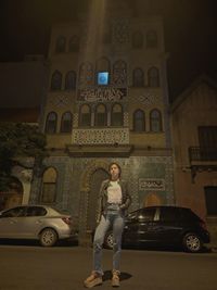 Full length portrait of woman standing against building