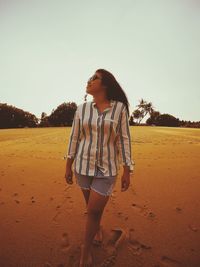 Woman looking away while standing on beach