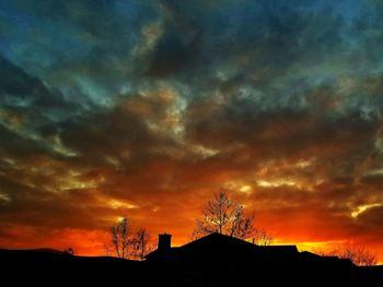 Low angle view of silhouette trees against dramatic sky