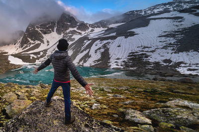 Traveler with outstretched arms to the sides stands at the foot of the mountain. a successful person