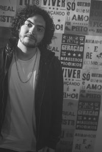 Portrait of young woman standing against graffiti wall