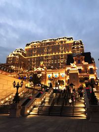 People on staircase of illuminated building in city at dusk