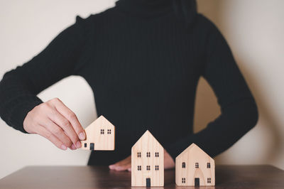 Midsection of man holding model house on table