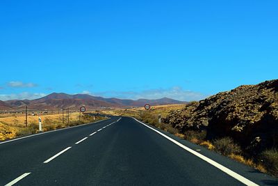 Road by mountains against clear blue sky