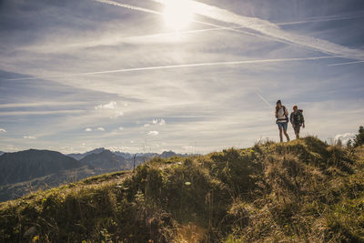 Man and woman walking on mountain trail in tannheimer tal, tyrol, austria