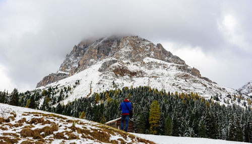 Rear view of man walking on field against mountain during winter