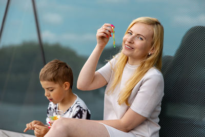 Happy blond woman and little boy sitting on terrace and eating sweets. mother and son enjoy 