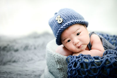 Close-up of cute baby boy lying down in basket on rug