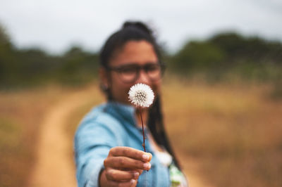 Portrait of man holding dandelion in field