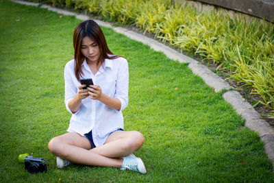 Young woman using mobile phone in grass