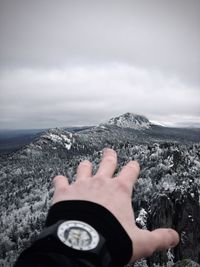 Midsection of person hand by sea against sky