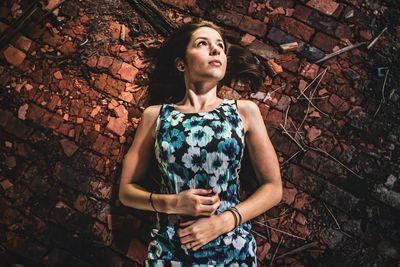 Directly above shot of thoughtful young woman lying down on brick floor