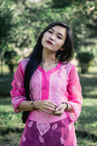 Portrait of beautiful young woman standing against pink petals