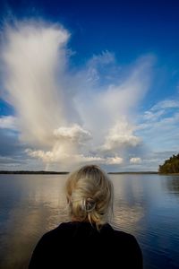 Rear view of woman looking at lake against sky