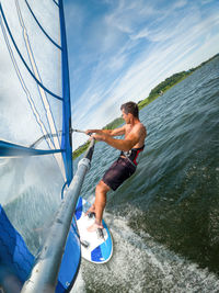 Wide-angle shot of adult man windsurfing on lake wallersee, austria.