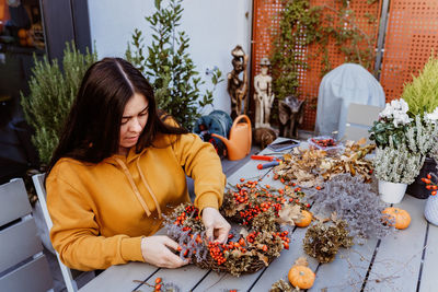 Woman making wreath while sitting by table at shop
