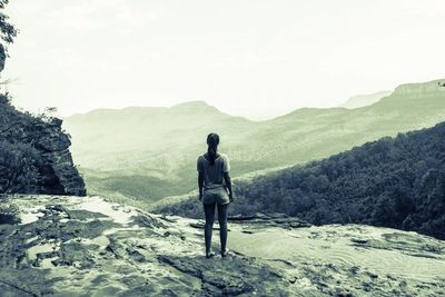 Rear view of woman standing on mountain against clear sky