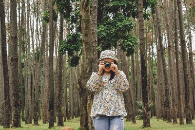 Young woman photographing through smart phone in forest