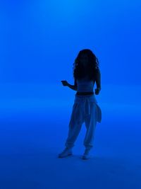 Low angle view of woman standing against blue sky