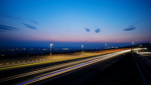 High angle view of light trails on highway against blue sky