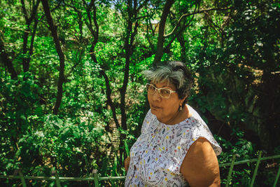 Woman with arms raised amidst trees in forest