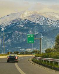 Road by snowcapped mountains against sky