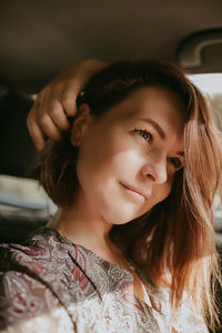  young woman with dark short hair and silver earrings sitting in the car at the window