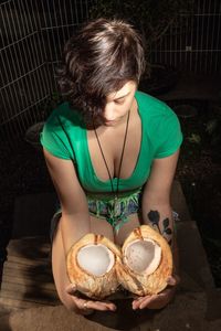 High angle view of woman holding coconut outdoors